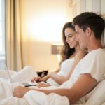 Happy couple using laptop on bed during weekend
