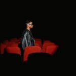 Man Black Leather Jacket Standing Behind Red Theatre Seat