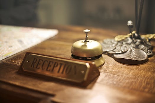 Old fashioned golden service bell and reception sign placed on wooden counter of hotel with retro interior
