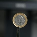 A coin is held in front of a computer screen